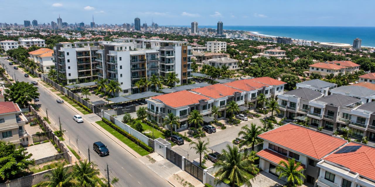 Aerial view of a Greater Accra residential neighborhood with apartment blocks, gated townhouses and the coastline beyond